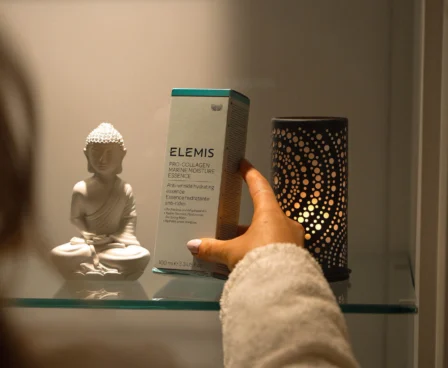 Guest picking Elemis skincare in serene hotel spa setting.