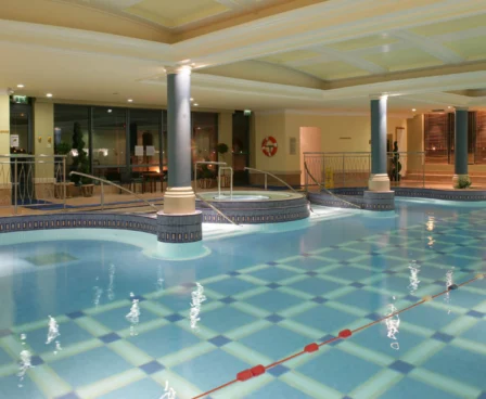 Indoor pool area at The Galmont Hotel, featuring elegant columns and inviting lounge spaces.