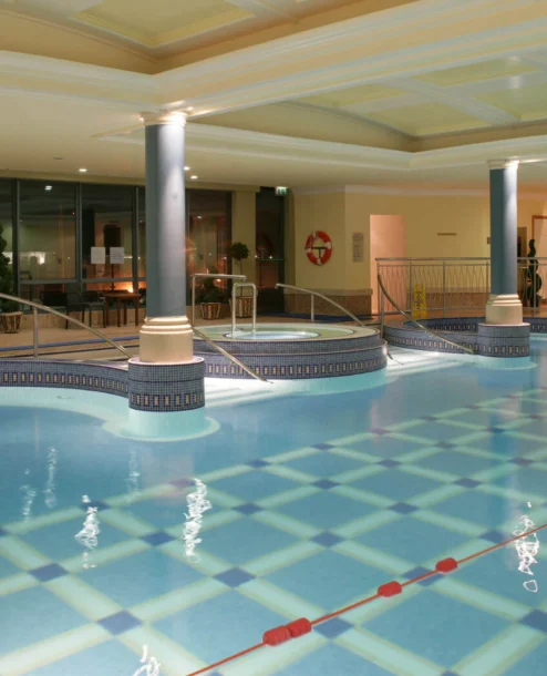 Indoor pool area at The Galmont Hotel, featuring elegant columns and inviting lounge spaces.