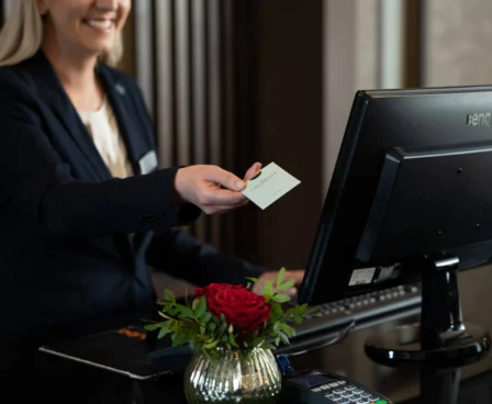 Hotel receptionist handing room key to smiling guest at The Galmont Hotel & Spa.