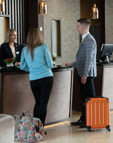A couple checks into The Galmont Hotel at a welcoming front desk with modern decor.