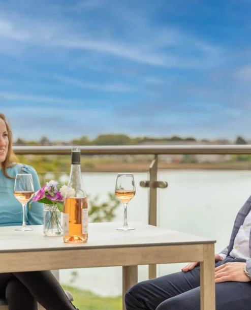 A couple enjoys wine on a balcony with a lake view at The Galmont Hotel & Spa.