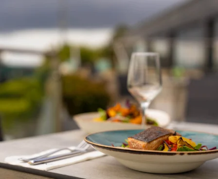 Outdoor dining with gourmet meal at The Galmont Hotel & Spa terrace, overlooking lush gardens.