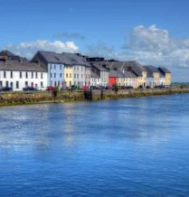 Picturesque waterfront view with colourful houses by The Galmont Hotel & Spa on a sunny day.