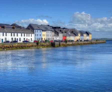 Picturesque waterfront view with colourful houses by The Galmont Hotel & Spa on a sunny day.