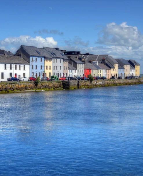 Picturesque waterfront view with colourful houses by The Galmont Hotel & Spa on a sunny day.