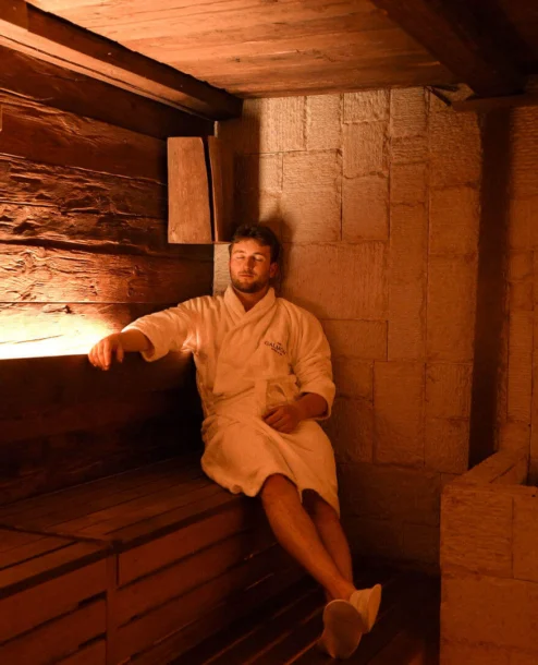 A person relaxes in a warmly lit wooden sauna at The Galmont Hotel & Spa.