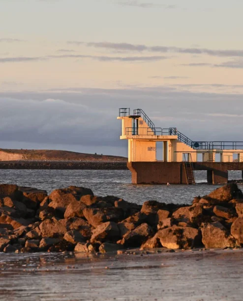 Family enjoying the beach near a diving platform at sunset by The Galmont Hotel & Spa.