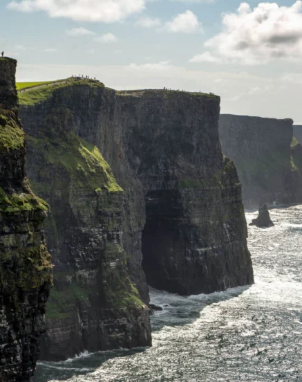 A breathtaking view of coastal cliffs under a cloudy sky with a distant horizon.