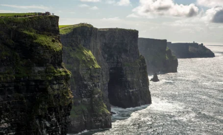 A breathtaking view of coastal cliffs under a cloudy sky with a distant horizon.