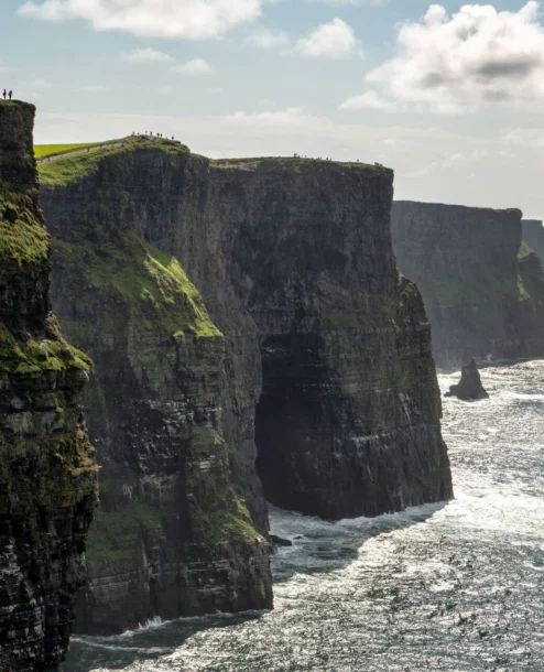 A breathtaking view of coastal cliffs under a cloudy sky with a distant horizon.