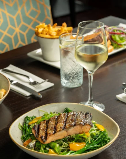 Gourmet meal with grilled salmon and wine at The Galmont Hotel & Spa restaurant.