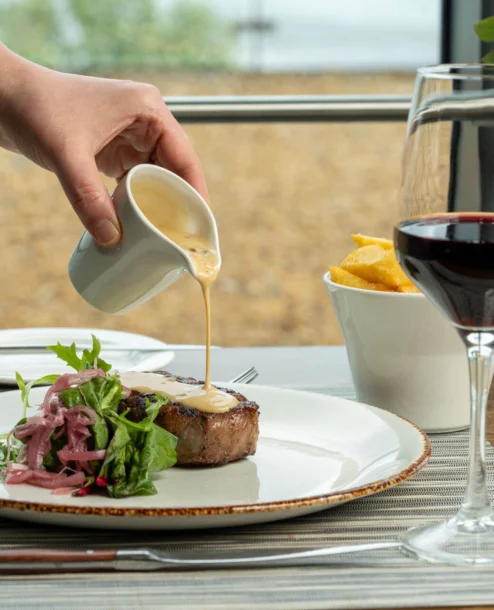 Elegant steak dinner in a cosy restaurant setting beside the sea.
