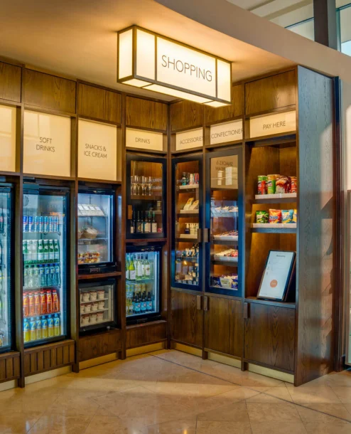 Hotel shop with refreshments and snacks display, warm lighting, cosy atmosphere.