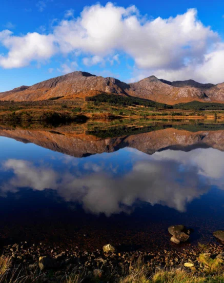Serene lake view with mountains and clouds reflected in the water.
