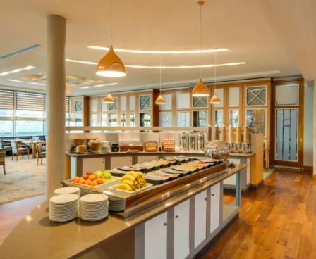 Bright hotel dining area with breakfast buffet and modern decor.