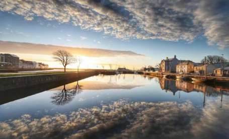 Serene sunset over a calm river beside The Galmont Hotel, reflecting the sky and scenic surroundings.