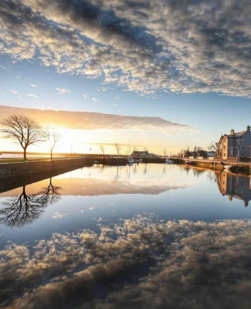 Serene sunset over a calm river beside The Galmont Hotel, reflecting the sky and scenic surroundings.