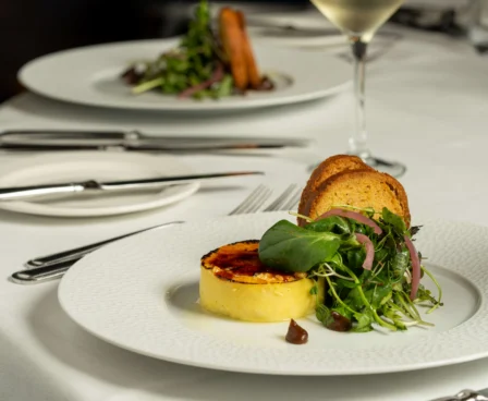 Elegant dining setup with gourmet starter and white wine at The Galmont Hotel.