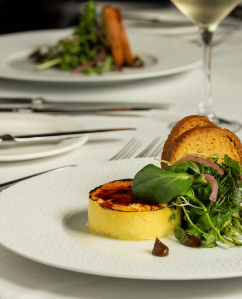 Elegant dining setup with gourmet starter and white wine at The Galmont Hotel.