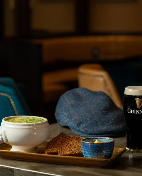 Cosy interior with soup, bread, and a pint on a table, setting a welcoming atmosphere.