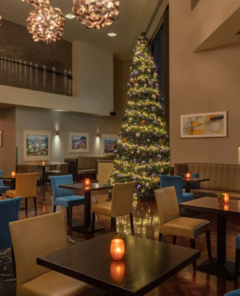 A warmly lit hotel dining area with festive Christmas decor and elegant seating.