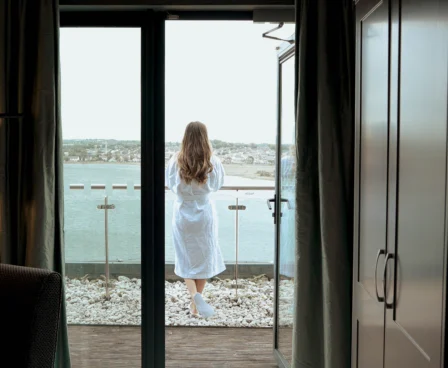 Woman in robe enjoying sea view from hotel balcony.