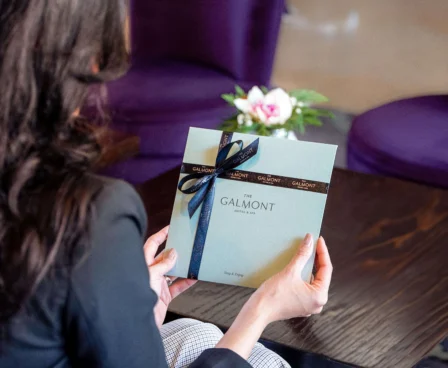 Woman holding The Galmont Hotel gift box in a cosy lounge setting.
