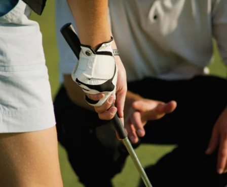 Family golfing lesson on lush green course at The Galmont Hotel & Spa. Hands-on guidance shown.