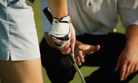 Family golfing lesson on lush green course at The Galmont Hotel & Spa. Hands-on guidance shown.