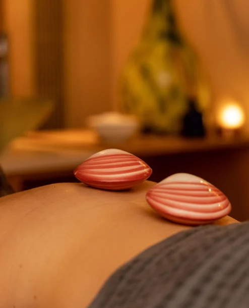 Spa guest enjoys relaxing hot shell massage at The Galmont Hotel, surrounded by warm lighting.