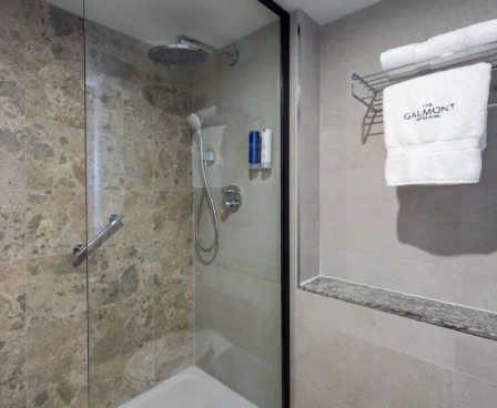 Elegant bathroom with marble shower and Galmont Hotel towel.