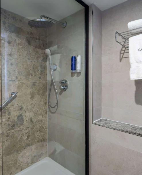 Elegant bathroom with marble shower and Galmont Hotel towel.
